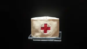 Ein historisches Armband des Roten Kreuzes auf einem Ausstellungsständer vor schwarzem Hintergrund.