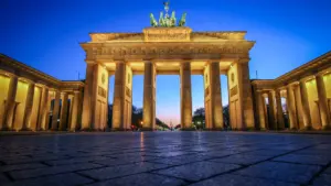 Das Brandenburger Tor in Berlin bei blauem Abendhimmel, menschenleer und stimmungsvoll beleuchtet.