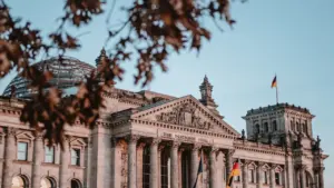 Die deutsche Flagge weht stolz vor dem Reichstagsgebäude in Berlin bei strahlendem Sonnenschein.