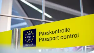 Gelbes Schild mit der Aufschrift Passkontrolle an einem internationalen Flughafen.