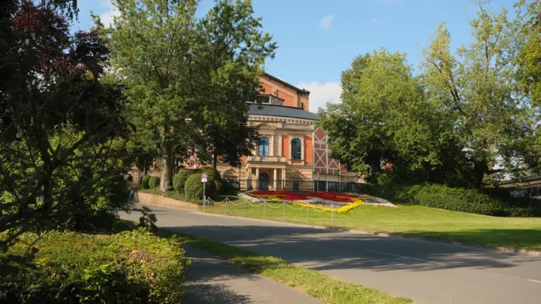 Ein elegantes, historisches Gebäude umgeben von üppigem Grün und einer asphaltierten Straße.