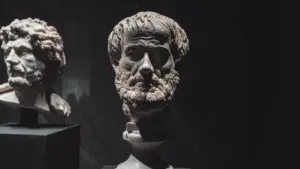 Zwei antike Marmorbüsten berühmter Philosophen stehen in einer dunklen Museums-Ausstellung zur Betrachtung bereit.