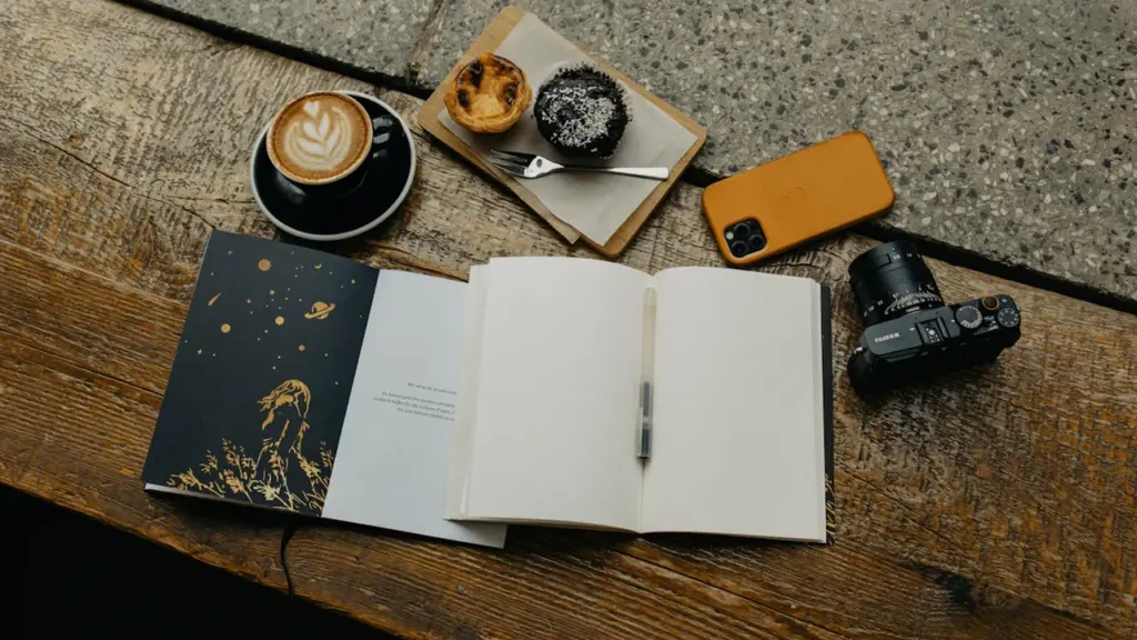 Ein offenes Notizbuch mit einer Tasse Kaffee auf einem hölzernen Tisch.