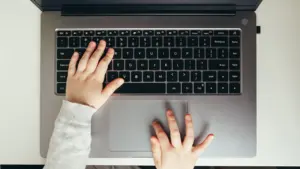Ein Kind tippt auf einer Laptop-Tastatur während eines Informatik-Workshops.
