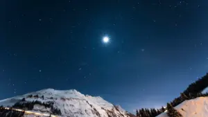 Verschneite Gipfel der Alpen unter einem klaren, funkelnden Sternenhimmel in der Nacht.