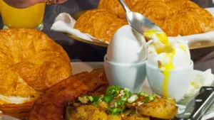 Gedeckter Frühstückstisch mit gekochtem Ei, frischen Croissants und Kartoffeln auf einem Schiff.