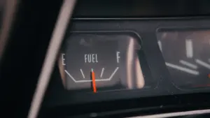 Nahaufnahme einer analogen Tankanzeige im Auto, die einen niedrigen Kraftstoffstand anzeigt.