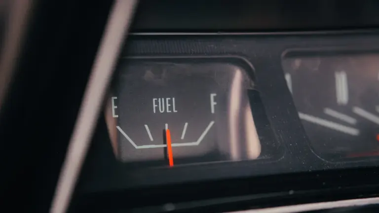 Nahaufnahme einer analogen Tankanzeige im Auto, die einen niedrigen Kraftstoffstand anzeigt.