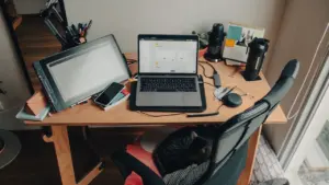 Ein aufgeräumter Homeoffice-Arbeitsplatz mit Laptop und Bildschirm an einem hölzernen Schreibtisch.