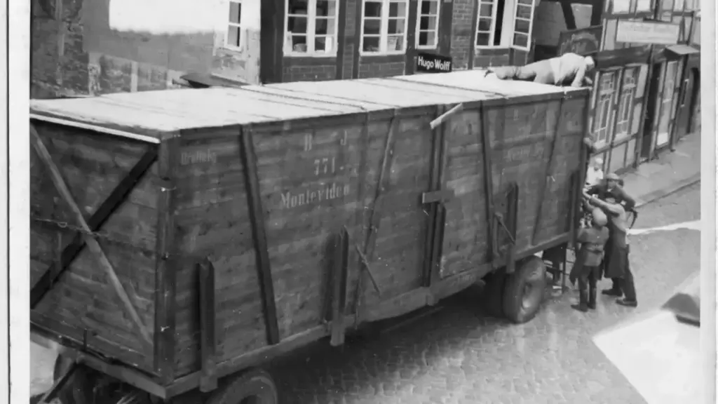 Ein großer hölzerner Transportanhänger mit der Aufschrift Montevideo steht in einer historischen deutschen Altstadtstraße.