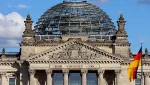 Das Berliner Reichstagsgebäude mit Glaskuppel und wehender deutscher Flagge im Sonnenlicht.