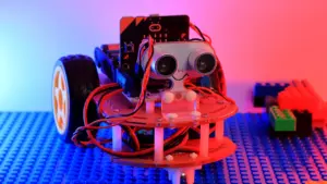 Ein kleiner Roboter aus Bausteinen auf einer blauen Unterlage beim Roboter-Quiz.