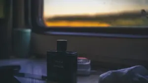 Ein edler Parfümflakon in einem Zugabteil bei untergehender Sonne, passend zum Thema Reise.