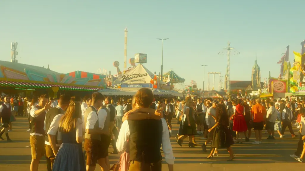 Menschen in traditioneller bayerischer Kleidung auf dem sonnigen Oktoberfestgelände in München bei Tageslicht.