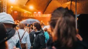 Menschenmenge beim Oktoberfest im Regen mit Regenschirmen bei einem Konzert.