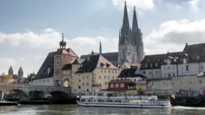 Blick auf die historische Steinerne Brücke und Regensburger Dom bei warmem Sonnenlicht.
