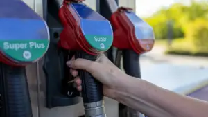 Eine Hand greift an einer Tankstelle zu einer Zapfpistole für Kraftstoff.