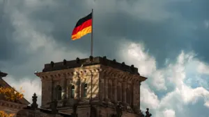 Die deutsche Flagge weht über dem historischen Gebäude bei bewölktem Himmel in Deutschland.