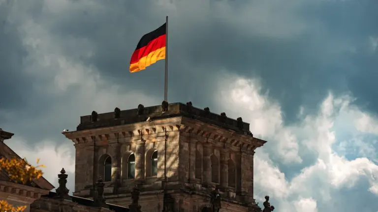 Die deutsche Flagge weht über dem historischen Gebäude bei bewölktem Himmel in Deutschland.