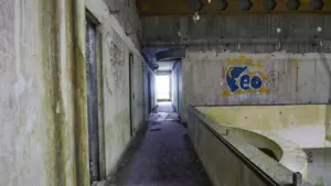 Verlassener Flur in einem alten deutschen Gebäude mit verwitterten Wänden und Graffiti.