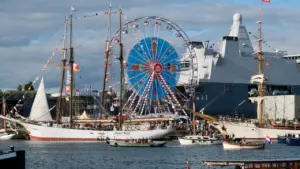 Großsegler und ein Riesenrad an der Hafenpromenade während eines sommerlichen Hafenfestes.