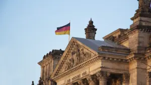Historisches Reichstagsgebäude mit der Inschrift Dem Deutschen Volke und wehender Flagge.
