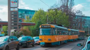 Gelbe Straßenbahn fährt in einer deutschen Stadt an einer Tankstelle vorbei.