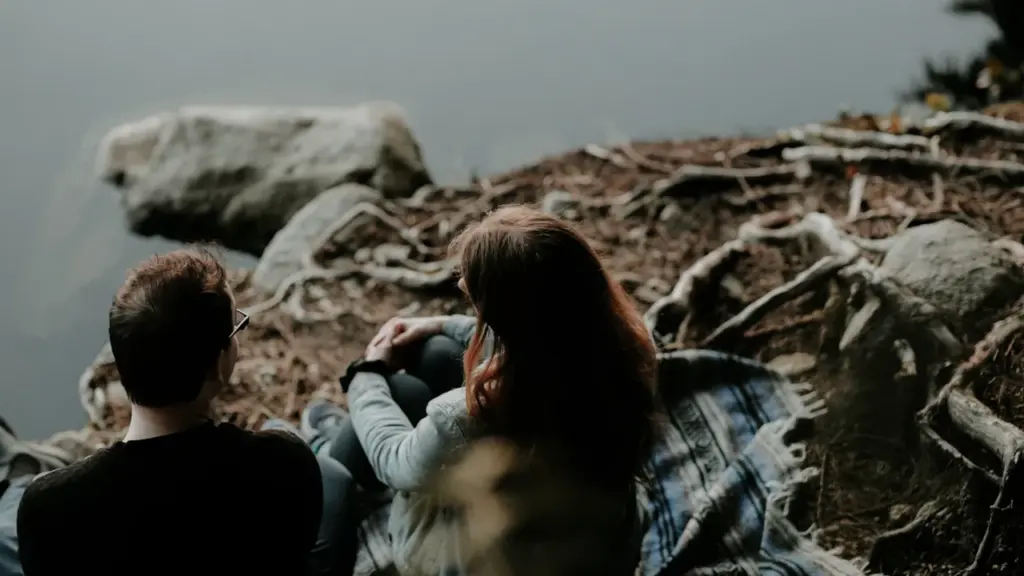 Ein Paar sitzt entspannt an einem Seeufer in der Natur.