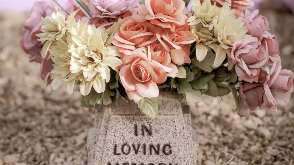 Ein Grabstein mit Blumen in liebevollem Gedenken an einen verstorbenen Menschen.