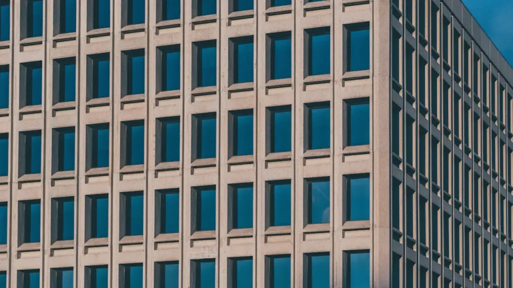 Architektonische Fassade eines modernen Bürogebäudes mit symmetrischen Fenstern unter blauem Himmel.
